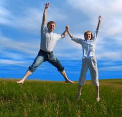 Healthy couple jumping in field